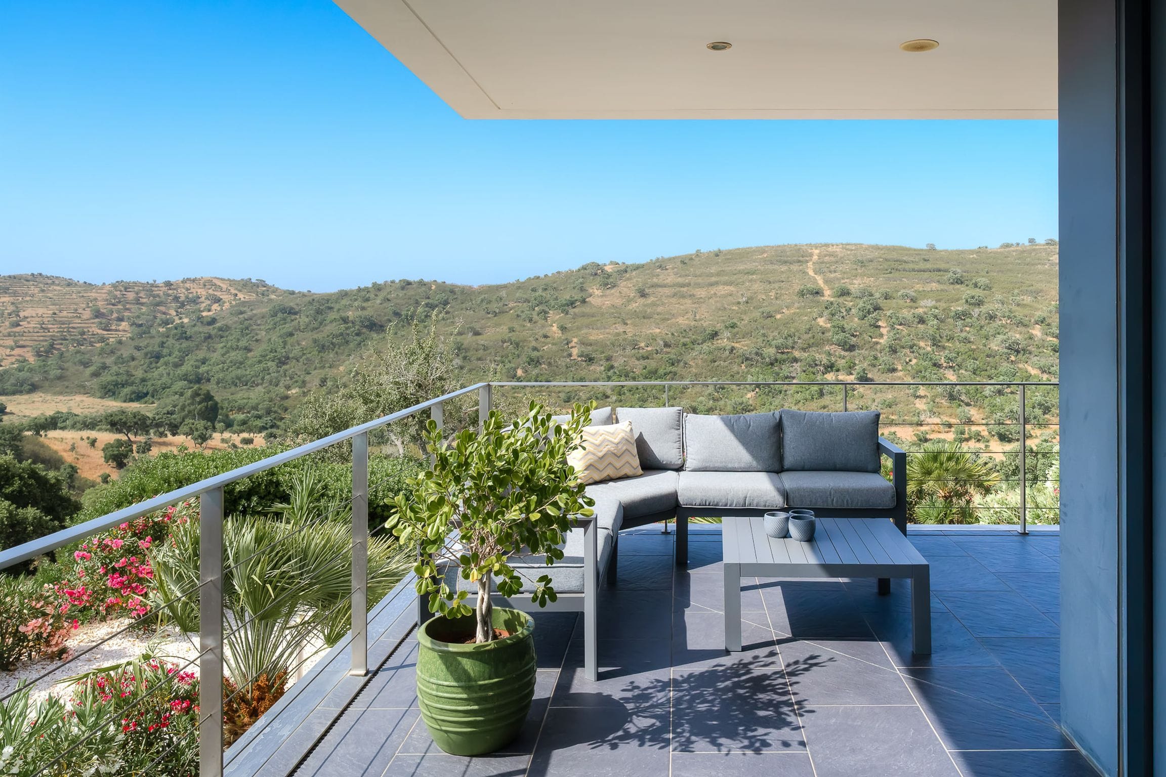 Outdoor lounge on the upper terrace looking out over green hills and a flowering garden